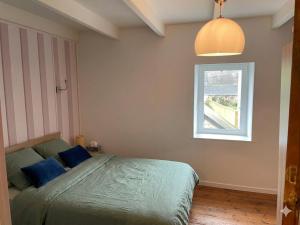 a bedroom with a bed with blue pillows and a window at Le Nid de Réville, Maison proche de la mer in Réville