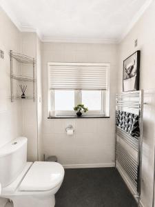 a white bathroom with a toilet and a window at Three Bed Detached Property in Frimley +7 photos