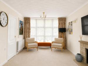 a living room with two chairs and a clock on the wall at Three Bed Detached Property in Frimley