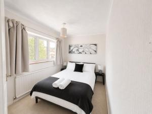 a bedroom with a bed with white sheets and a window at Three Bed Detached Property in Frimley