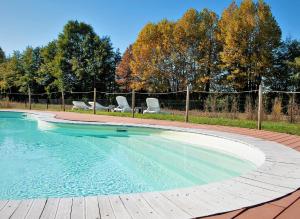 a swimming pool with two chairs and a fence at Agriturismo Corte La Sacca in Pozzolengo