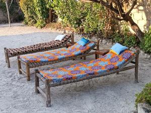 three benches with colorful pillows sitting on the ground at Jambiani Holiday House in Jambiani