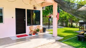 a front porch with a black door and an american flag at Homestay Seri Aishah in Chemor
