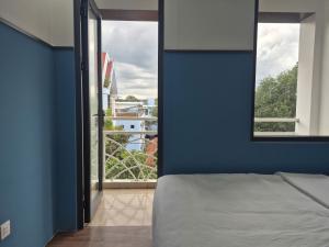 a bedroom with a blue wall with a bed and a window at Hyper house hotel in Buôn Ðũng