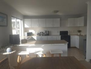 a kitchen with white cabinets and a table and chairs at Sea Echo in Yzerfontein