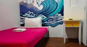 a bedroom with a pink bed with a painting on the wall at Dormitelsph BGC in Manila