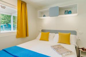 a bedroom with a bed with yellow pillows and a window at Massa Marina Camping in Marina di Massa