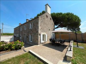 a brick building with a table and chairs and an umbrella at Le Nid de Réville, Maison proche de la mer in Réville
