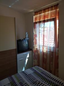 1 dormitorio con 1 cama, TV y ventana en Apartments Batovanja en Vir