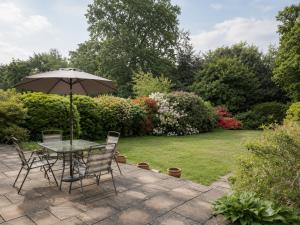 a table and chairs with an umbrella in a garden at Three Bed Detached Property in Frimley
