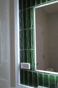 a bathroom mirror with green glass tiles on the wall at โรงแรมเดย์โฮเต็ล in Khon Kaen