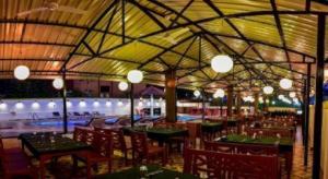 a restaurant with tables and chairs and a swimming pool at Hotel Colva Kinara in Colva