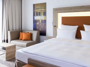 a bedroom with a large bed and a couch at Novotel Nürnberg Centre Ville in Nuremberg +84 photos