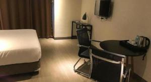 a hotel room with a bed and a table and a television at Maxx Hotel Ortigas in Manila
