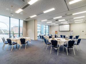 a conference room with tables and chairs and a screen at Pullman Liverpool in Liverpool