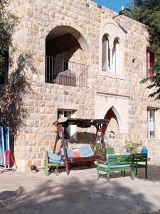 two green benches sitting in front of a building at Khalle lodge in Dayr al Qamar