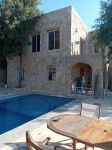 a villa with a swimming pool and a table and a patio at Khalle lodge in Dayr al Qamar