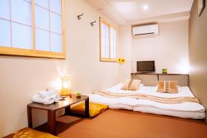 a bedroom with two beds and a table at Hotel 向日葵 in Osaka