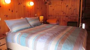 1 dormitorio con 1 cama grande y paredes de madera en The Retreat on Matthew en Batehaven