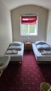 two beds in a small room with a window at Fengselet Gjestegård in Leira