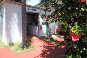uma garagem branca com árvores e flores vermelhas em Matildas End Holiday Units em Karumba