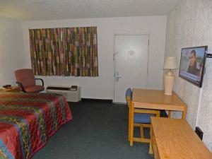 a hotel room with a bed and a table and a window at Plaza Inn in Topeka