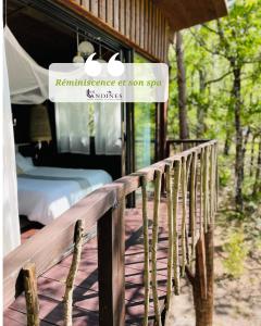 a wooden deck with a bed and a sign on a house at Cabanes et Spa Les Landines in Origne