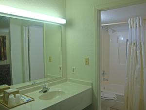 a bathroom with a shower, sink, and mirror at Plaza Inn in Topeka