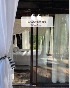 a sign in a window of a bedroom with a bed at Cabanes et Spa Les Landines in Origne