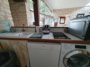 a kitchen with a sink and a washing machine at Le pressoir du prieuré in Ligré