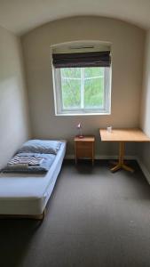 a bedroom with a bed and a desk and a window at Fengselet Gjestegård in Leira +19 photos