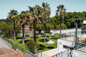 a resort with a swimming pool and palm trees at Refúgio da Mel - Piscinas e Praia fluvial próximas in Alandroal