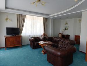 a living room with leather couches and a television at Hotel Metropol – Metropol Lake Resort in Ohrid