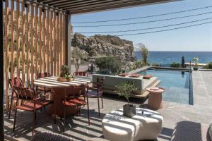 a patio with a table and chairs and a swimming pool at Lapis Nera Villas - Beachfront & "Free" Heated Pools in Psari Forada