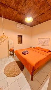 a bedroom with a bed with an orange comforter at Alianna Homestay in Karimunjawa