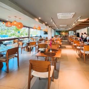 a restaurant with wooden tables and chairs and people at Malia Beach - Muro Alto - Porto de Galinhas - Cozinha equipada in Porto De Galinhas