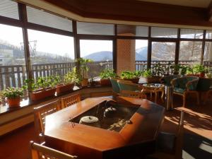 ein Zimmer mit Tisch, Stühlen und Fenstern in der Unterkunft Hotel Tagawa in Yamanouchi