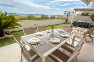 a white dining table and chairs on a patio at Beachfront Reiterer Villa V1 with Jacuzzi 30 meters from the Beach - CROWONDER LUXURY RENT in Privlaka