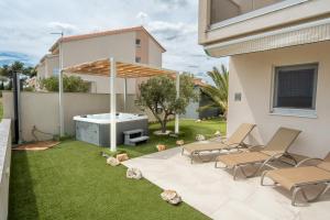a backyard with a hot tub and chairs and an umbrella at Beachfront Reiterer Villa V1 with Jacuzzi 30 meters from the Beach - CROWONDER LUXURY RENT in Privlaka