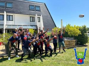 a group of people standing in the grass with their hands in the air at Ibis Styles Toulouse Labège in Labège