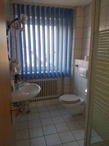 ein Bad mit einem WC, einem Waschbecken und einem Fenster in der Unterkunft Hotel Stadt Baunatal in Baunatal