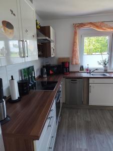 a kitchen with white cabinets and a sink and a window at Ferienwohnung Milans Eck in Schwienau
