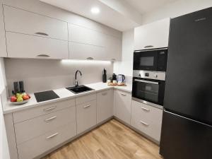 a kitchen with white cabinets and black appliances at Veleslaveenka - Spacious Apartment in Pilsen Old Town in Pilsen