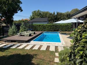 a small swimming pool in a yard with an umbrella at MARINA HOUSE pool & garden in Beograd