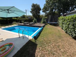 a swimming pool with an umbrella next to a yard at MARINA HOUSE pool & garden in Beograd +16 photos