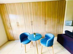 a living room with two blue chairs and a table at Parklane Bed and breakfast in Gaborone