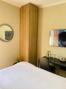 a bedroom with a bed and a desk and a mirror at Parklane Bed and breakfast in Gaborone