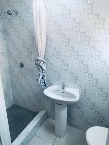 a white bathroom with a sink and a shower at Parklane Bed and breakfast in Gaborone