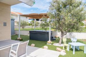 a backyard with a table and chairs and a tree at Beachfront Reiterer Villa V3 with Jacuzzi 30 meters from the Beach - CROWONDER LUXURY RENT in Privlaka