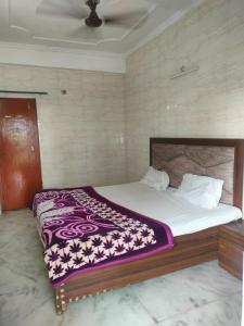 a bedroom with a large bed with a purple blanket at Shri Ram seva sadan in Vrindāvan